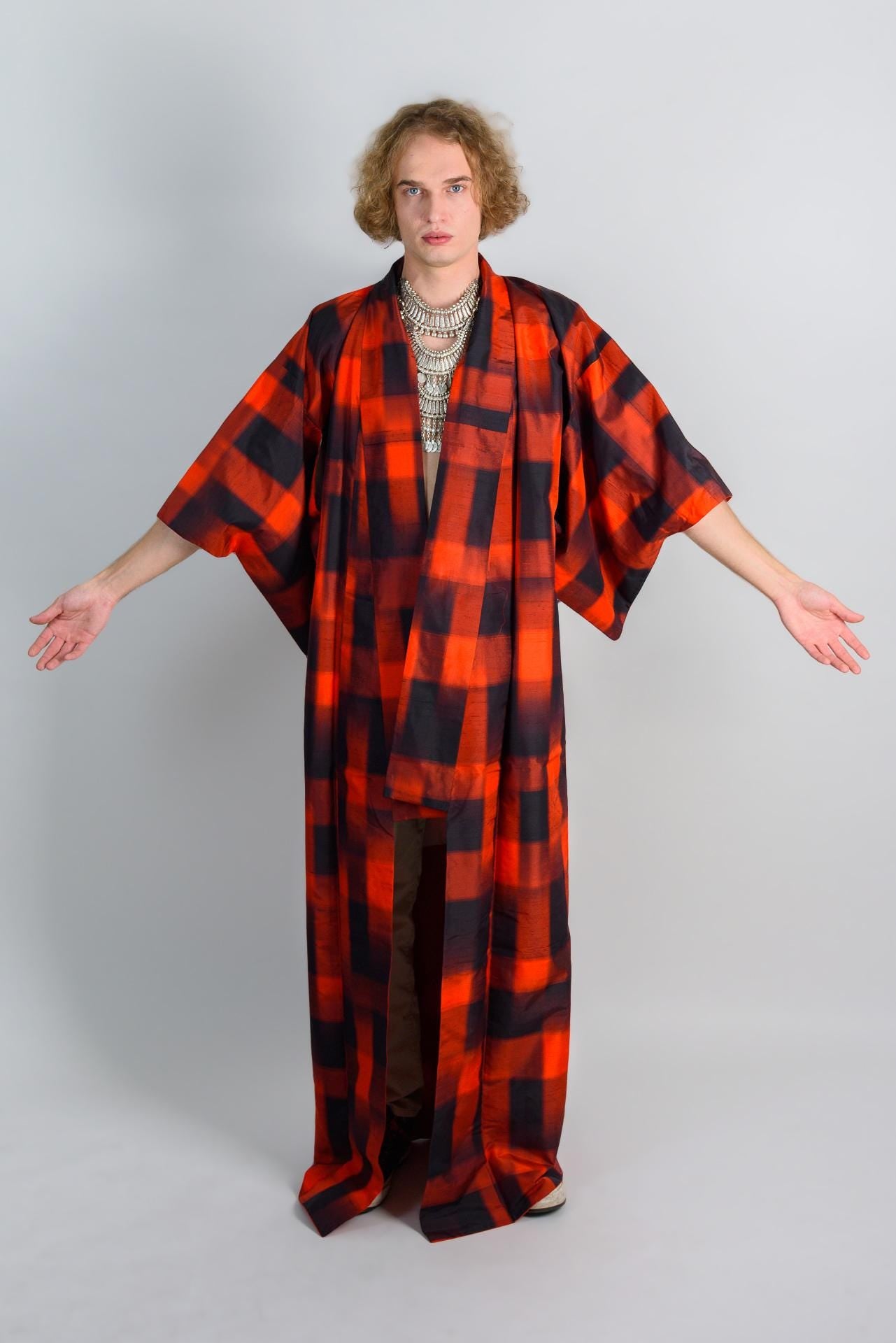 May include: A person wearing a red and black plaid kimono with a silver necklace.