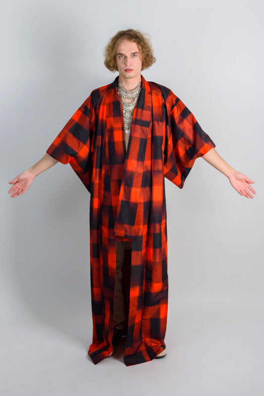 May include: A person wearing a red and black plaid kimono with a silver necklace.