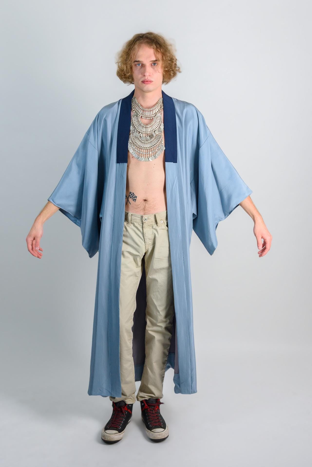 May include: A light blue long-sleeved robe with a dark blue collar and a silver necklace.