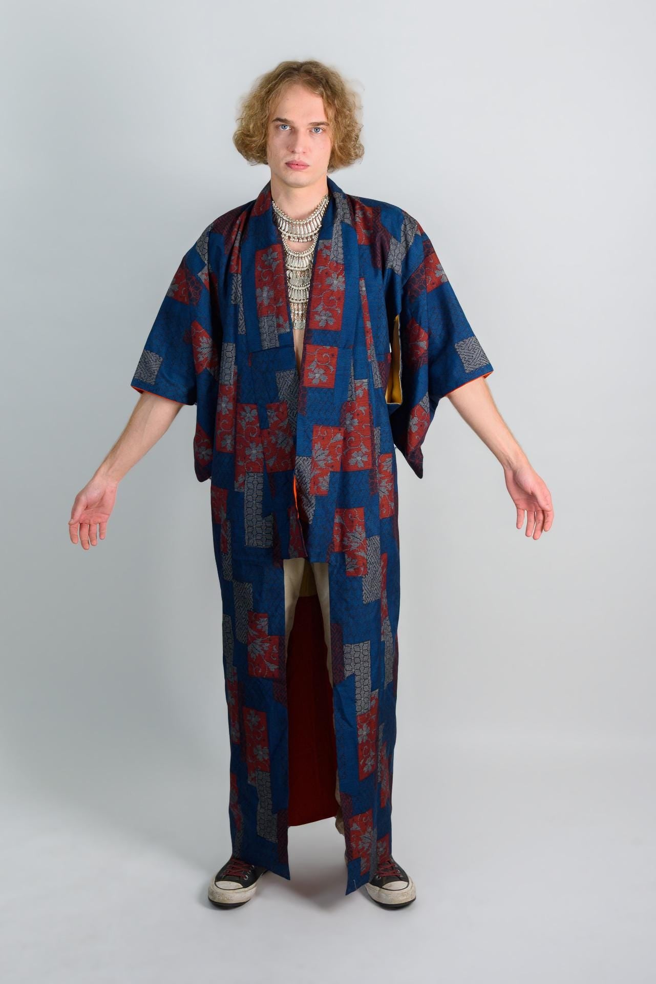 May include: A long, blue and red patterned robe with a white collar and a silver necklace.