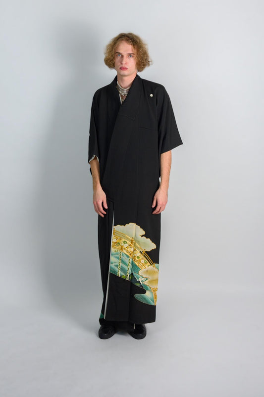 May include: A black kimono with a green and gold design. The kimono is worn by a person with curly blonde hair.