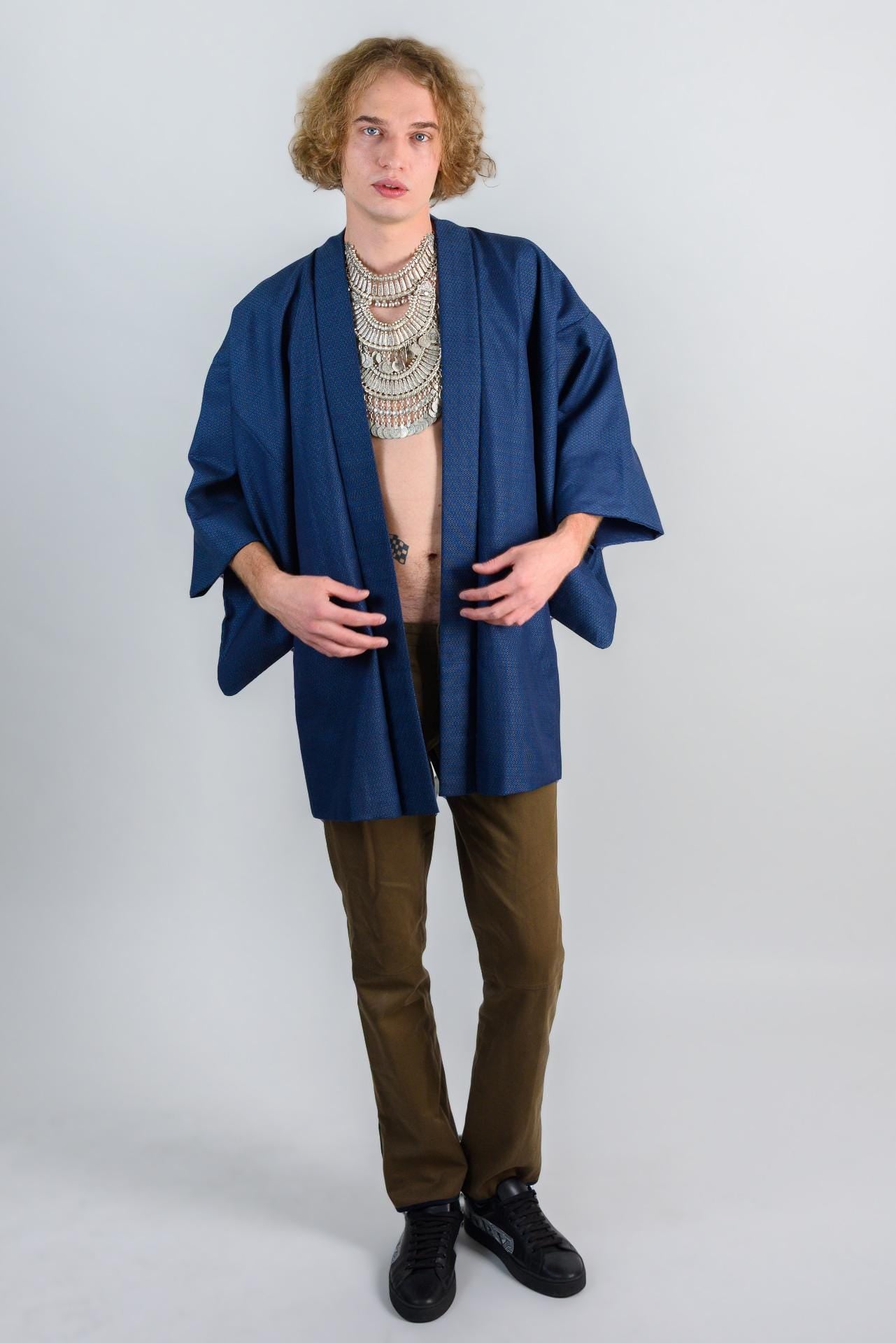 May include: A blue denim kimono with long sleeves and a brown pants.