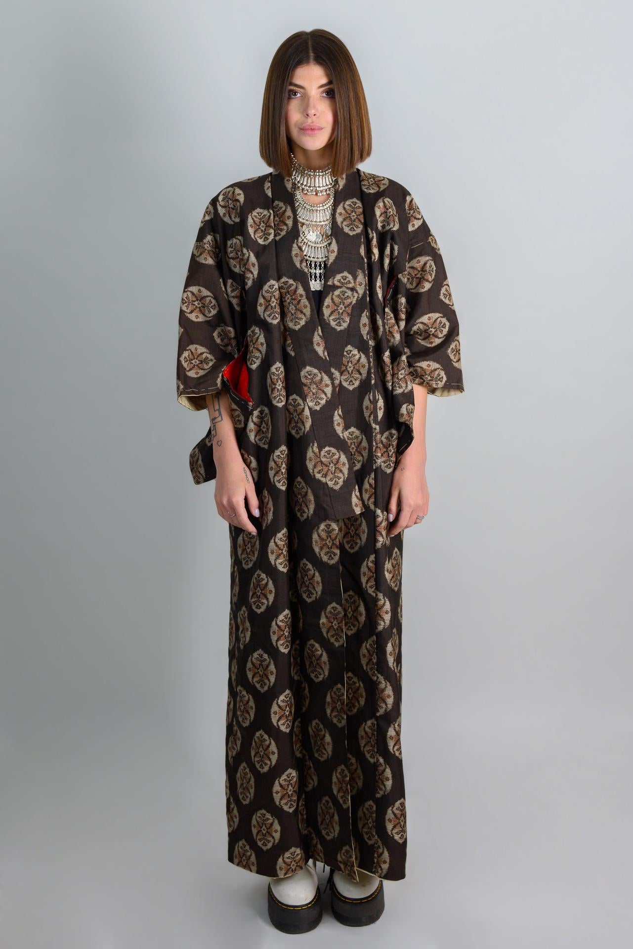 May include: A long black and brown patterned kimono with a silver necklace.