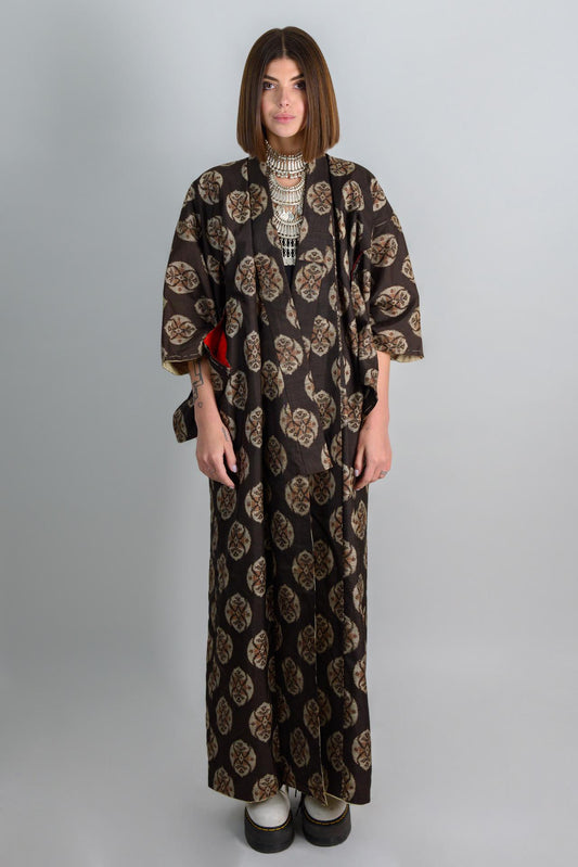 May include: A long black and brown patterned kimono with a silver necklace.