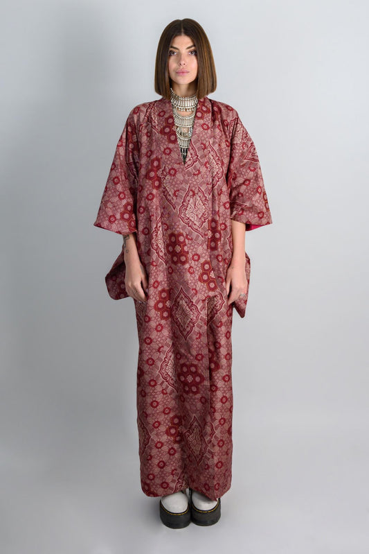 May include: A long, red and pink patterned robe with a V-neckline. The robe has a loose fit and is made of a silky fabric.