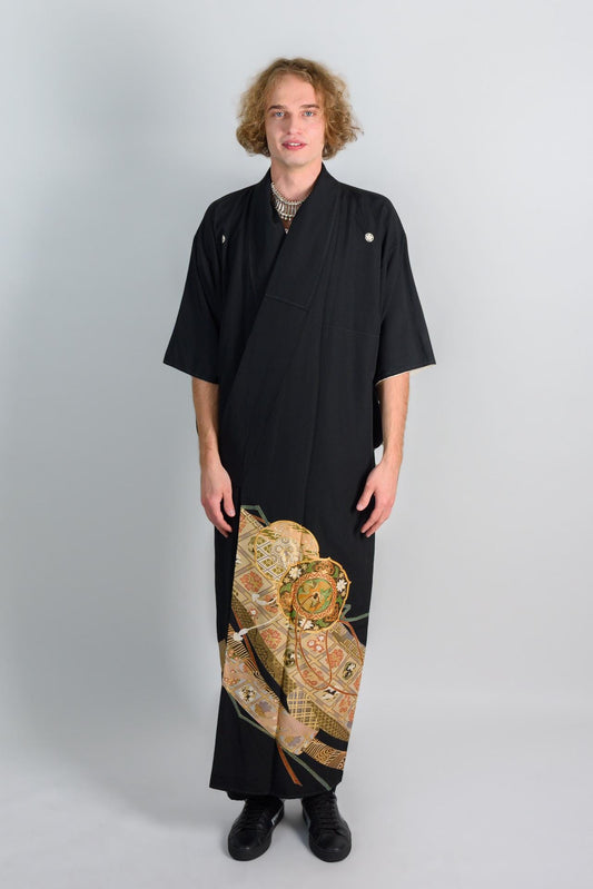 May include: A black kimono with a gold and green patterned design on the bottom half of the garment.