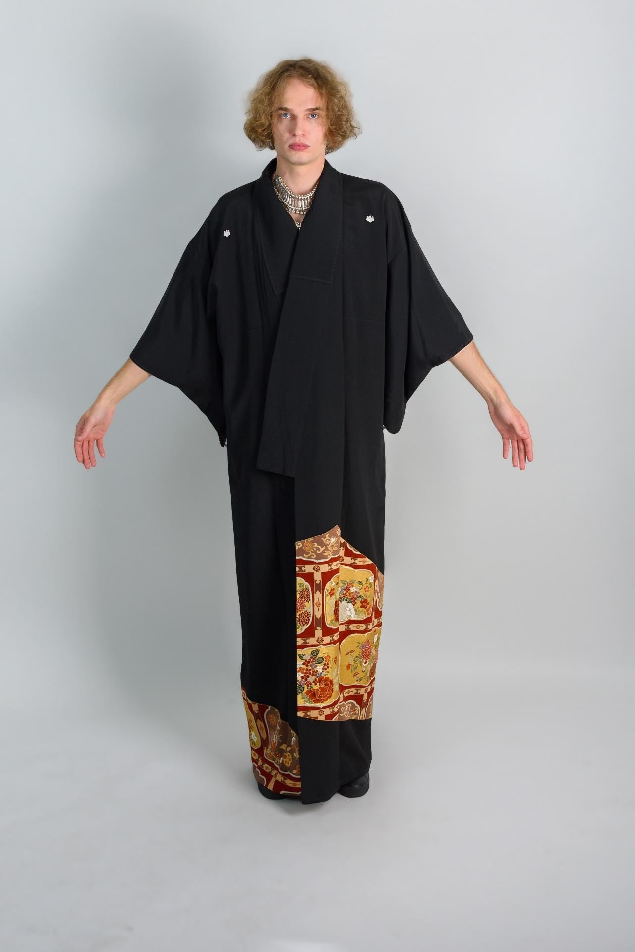 May include: A black kimono with a colorful patterned bottom hem. The kimono has a long sleeve and a simple design.