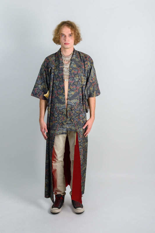 May include: A long, dark blue and green patterned robe with a red lining. The robe has a floral pattern and is worn over a pair of light brown pants and black sneakers.