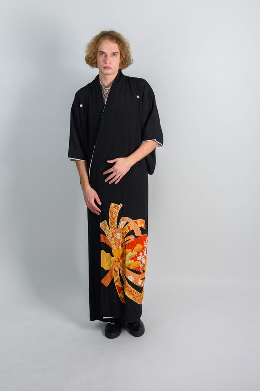 May include: A black kimono with a colorful floral pattern on the bottom half. The kimono has a white trim around the sleeves and collar.