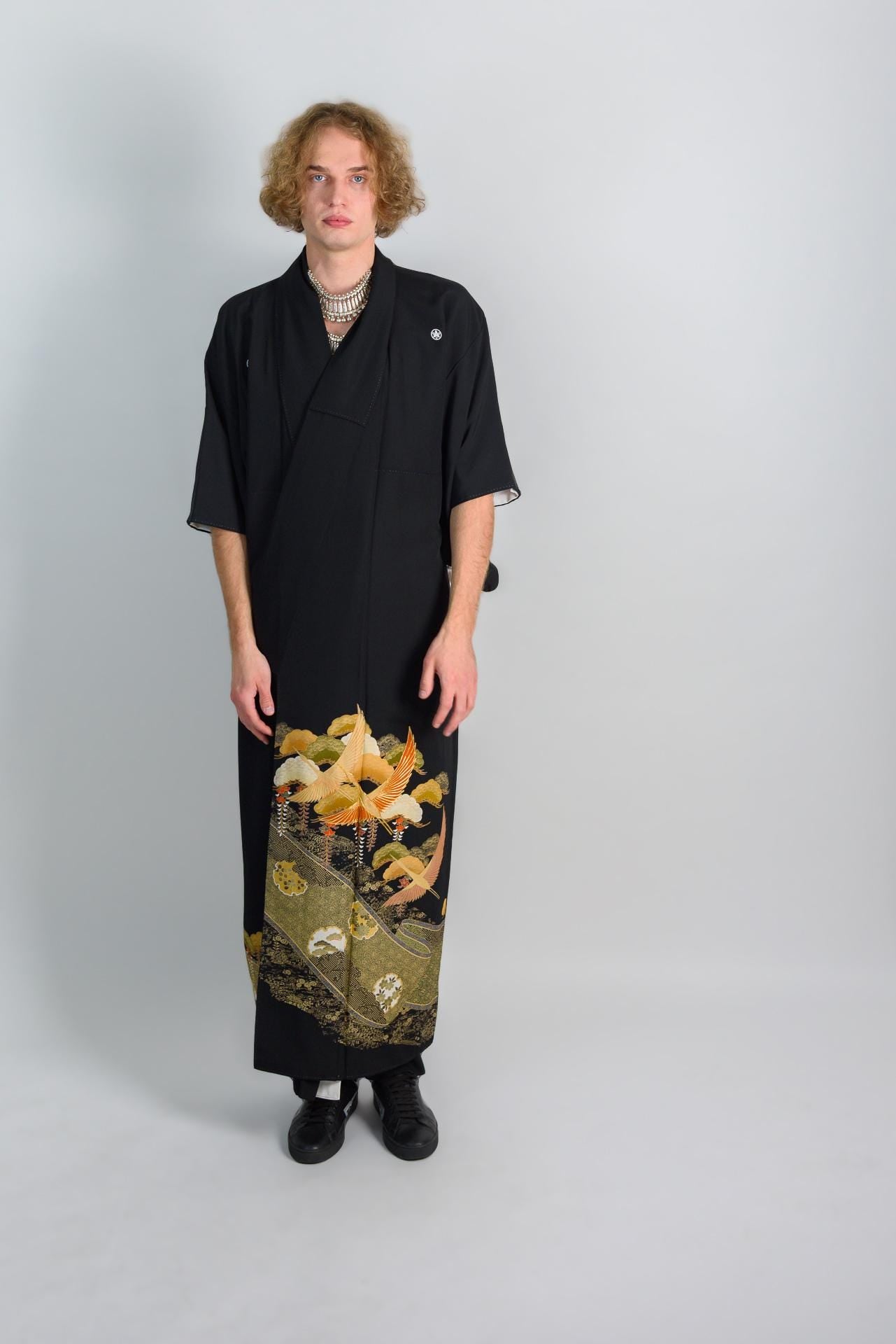 May include: A black kimono with a floral pattern on the bottom hem. The kimono has a simple design and is made of a soft, flowing fabric.