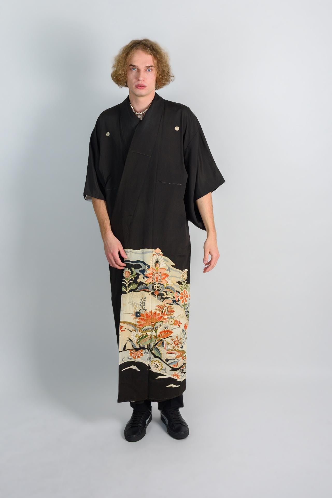 May include: A black kimono with a floral pattern on the bottom half. The kimono has a simple design and is made of a soft, flowing fabric.