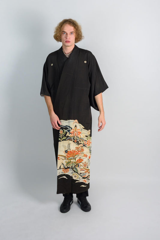 May include: A black kimono with a floral pattern on the bottom half. The kimono has a simple design and is made of a soft, flowing fabric.